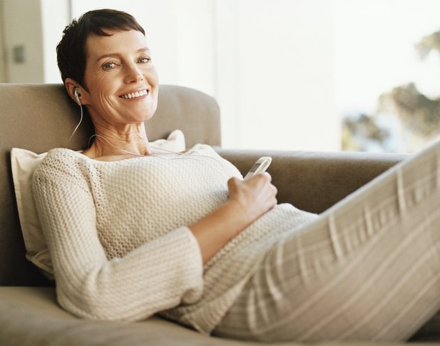 Mature Woman Lies on a Chaise-Lounge Wearing an Earpiece and Holding a Mobile Phone