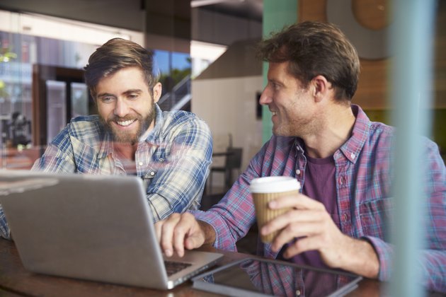 Two Businessmen Working On Laptop In Coffee Shop