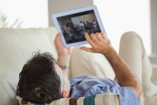 Man laying on a sofa using a tablet pc