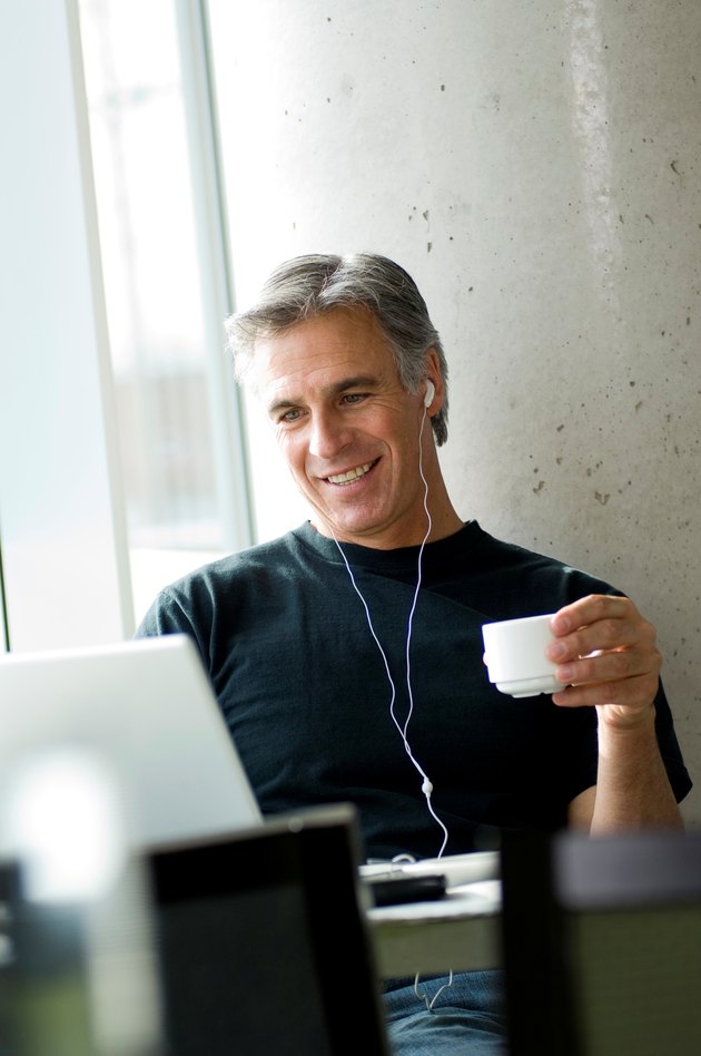 Middle-aged man listening to music in urban cafe.