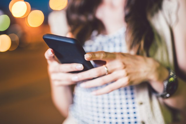 Woman holding mobile phone at night time. Close up.