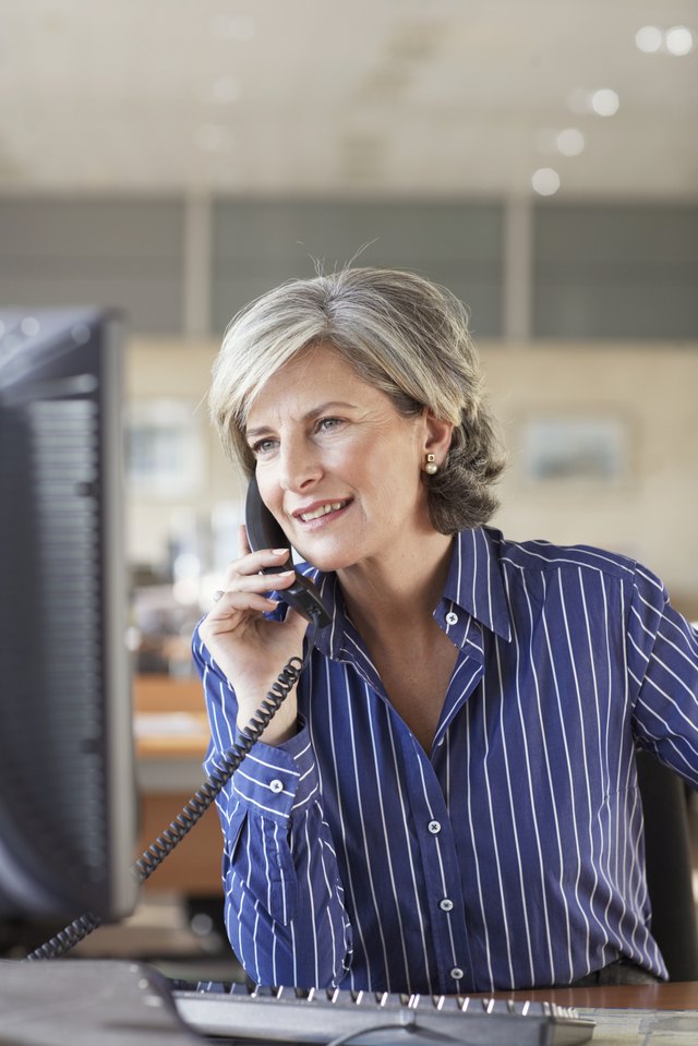 Mature businesswoman using telephone in office