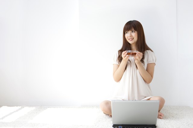 Young woman holding cup of tea, looking away, white background, copy space