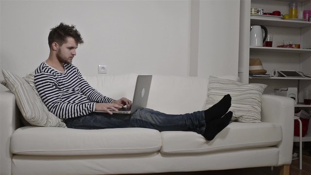 Young man working on laptop sitting on the couch
