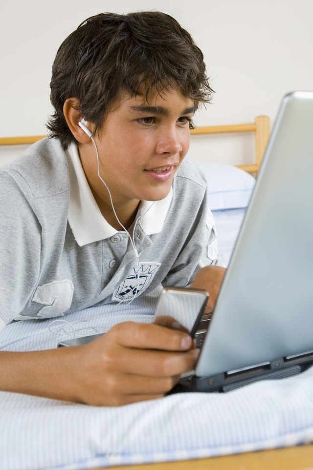 Teenage boy using laptop computer and mp3 player