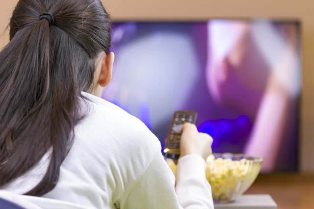Relaxed teenage girl with remote control watching smart TV