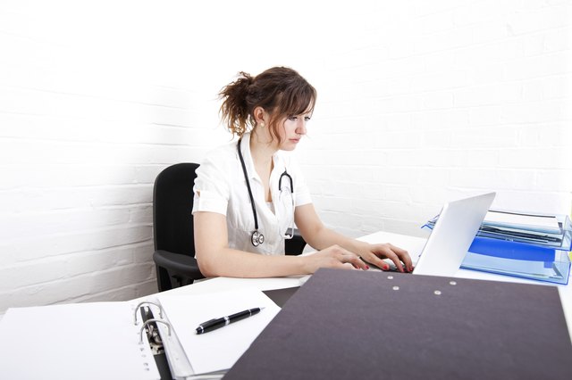 Young female doctor using laptop at desk in clinic