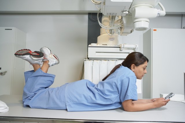 Indian female nurse laying on table using cell phone