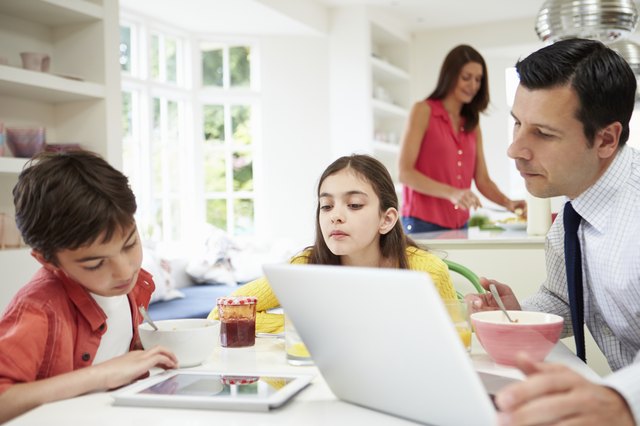 Family Using Digital Devices At Breakfast Table