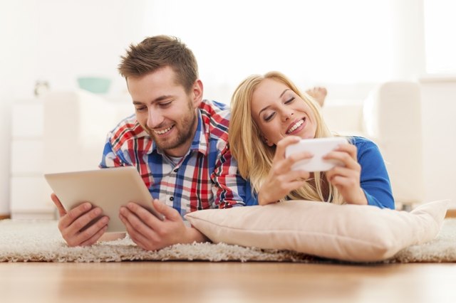 Happy couple spending time with electronic equipment at home