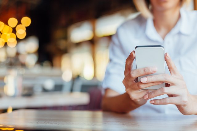 Woman holding mobile phone in a cafe