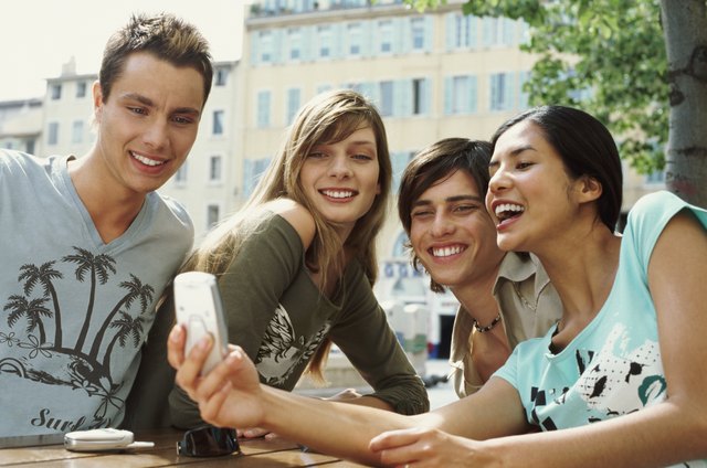 Four Teens Sitting at a Table and Using a Videophone