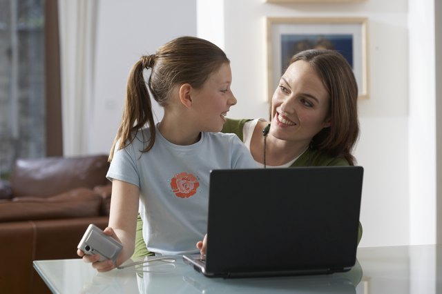 Mother and daughter (9-11) using laptop computer, smiling