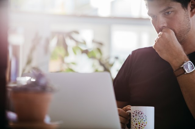 Serious male executive looking at laptop