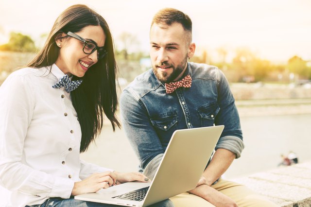 Couple of hipster friends using laptop in the city