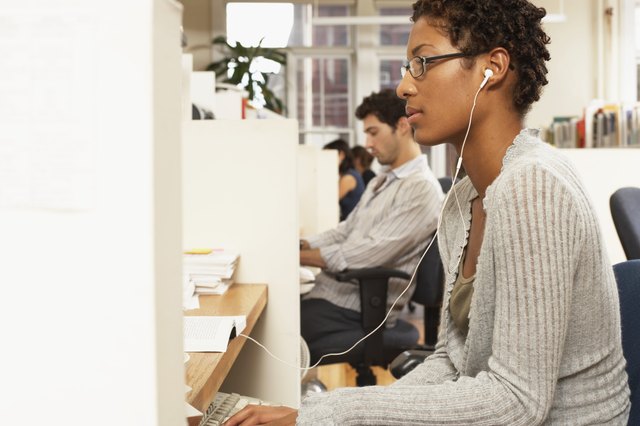 Female office worker at desk, wearing earphones