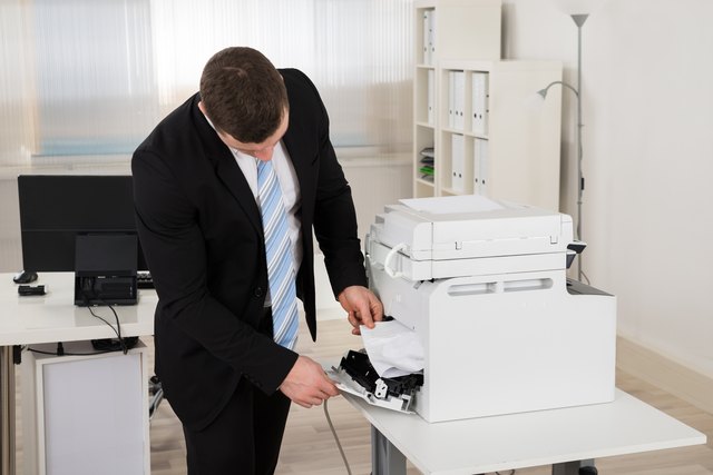 Businessman Removing Paper Stuck In Printer