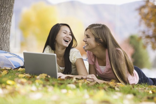 Teenage girls using laptop outdoors