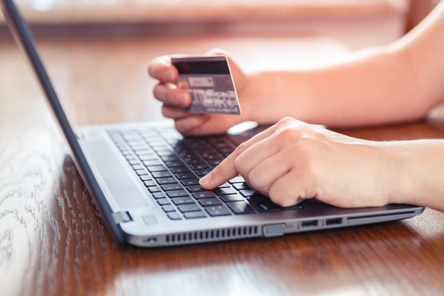 Hands holding credit card and using laptop - online shopping