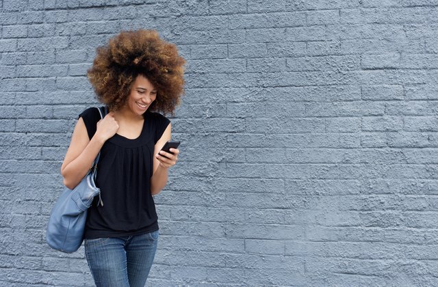 Smiling woman walking and looking at mobile phone