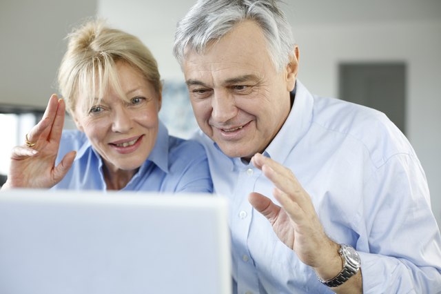 Senior couple at home using internet to talk with friends